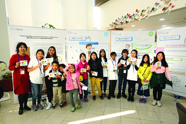 지난 13일 국립 어린이 청소년 도서관에서 열린 어린이 건강 증진 행사 ‘네슬레 포 헬시어 키즈’에 참석한 어린이들이 GYF 자원봉사자들과 기념 촬영을 하고 있다. 사진=네슬레코리아 제공